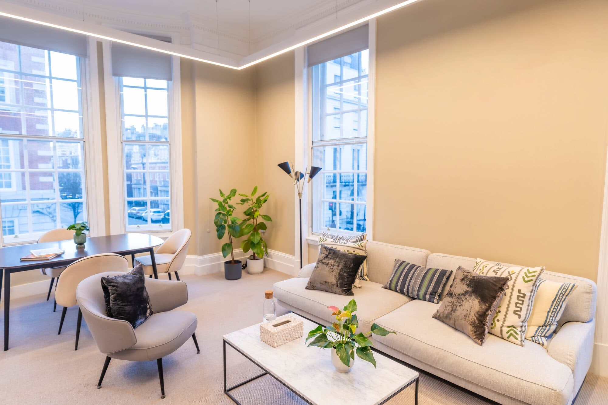 A consulting room at the London Psychiatry Clinic, with a sofa and armchairs beside tall sash windows
